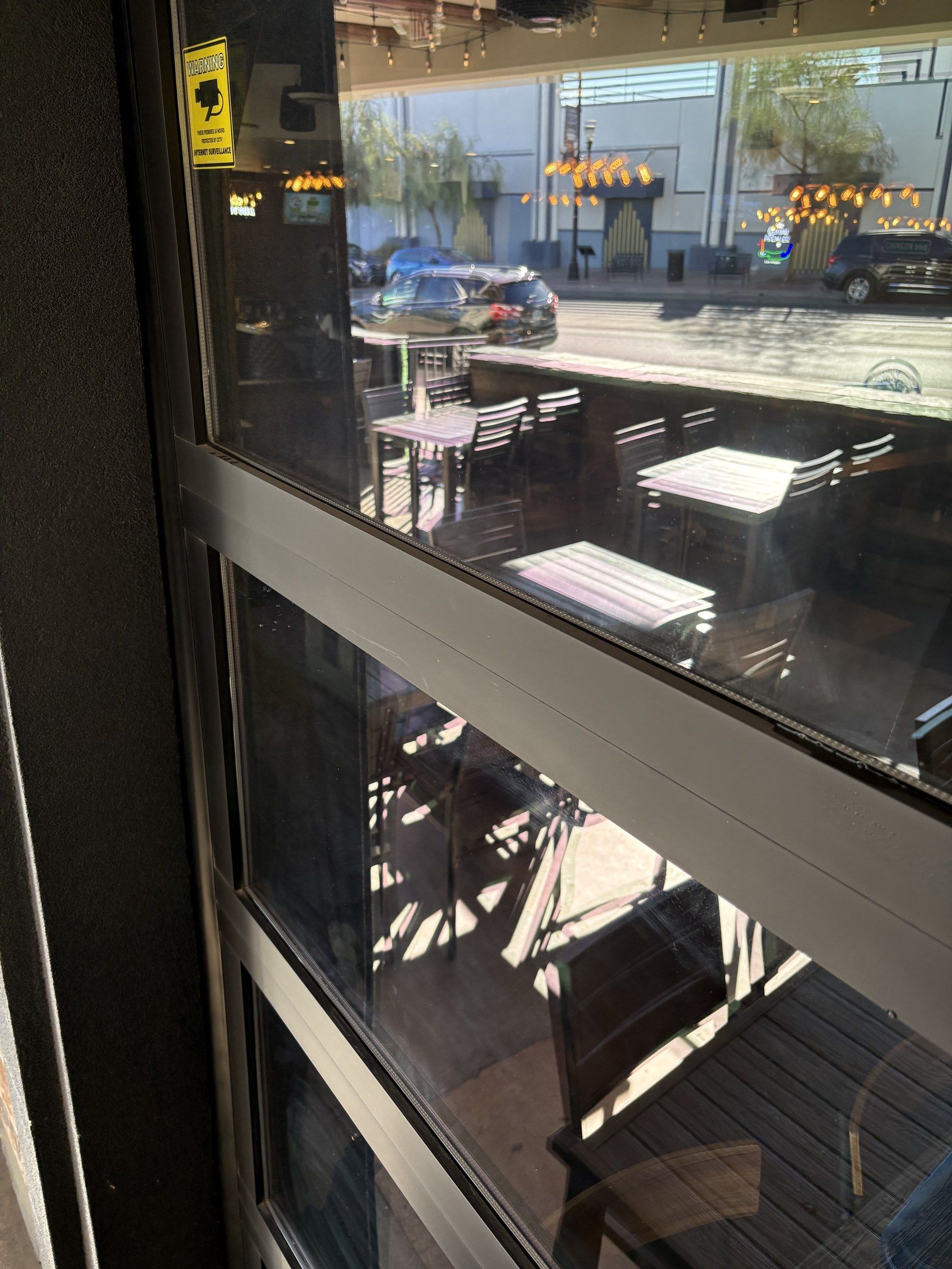 View through clean commercial glass onto a sunny patio and the street outside